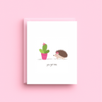 Greeting card with a hedgehog and cactus illustration on a pink background